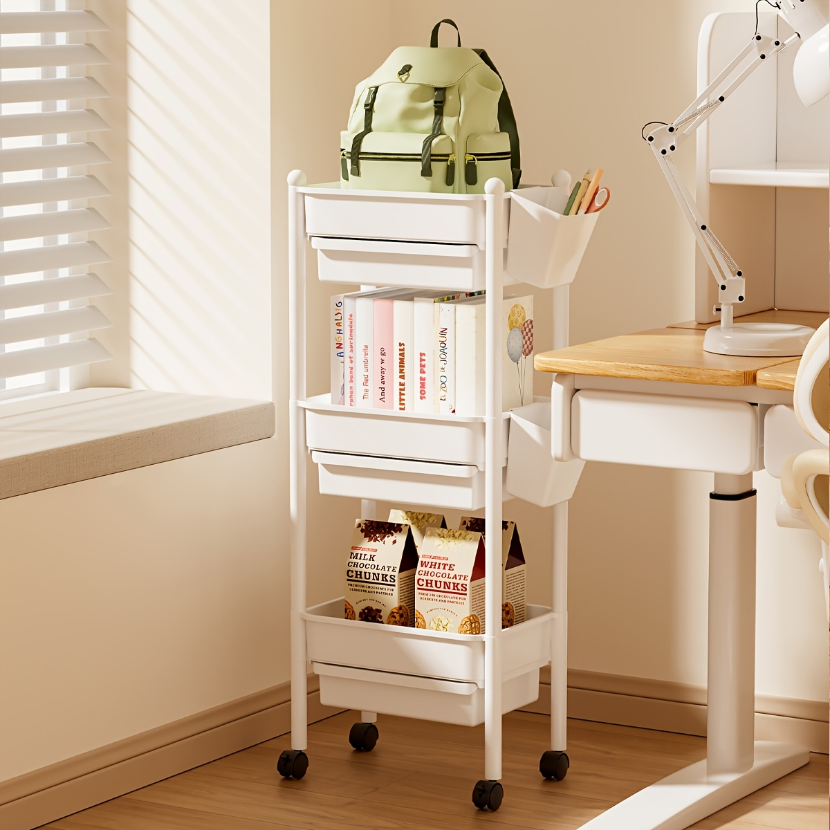 Three-tiered bookshelf with wheels, and includes two pen holders.